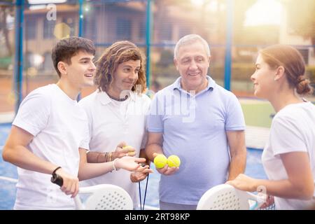 Vier Paddle-Tennisspieler sprechen auf dem Platz Stockfoto