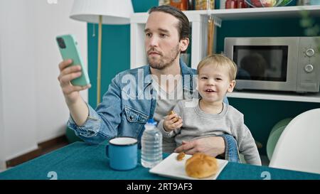 Vater und Sohn frühstückten mit dem Smartphone im Speisesaal Stockfoto