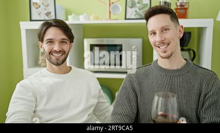 Zwei Männer, die selbstbewusst ein Glas Wein im Speisesaal trinken Stockfoto