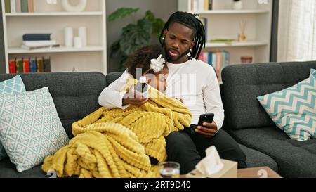 afroamerikanischer Vater und Tochter, die krank sind und zu Hause nach Informationen zu Medikamentenflaschen suchen Stockfoto