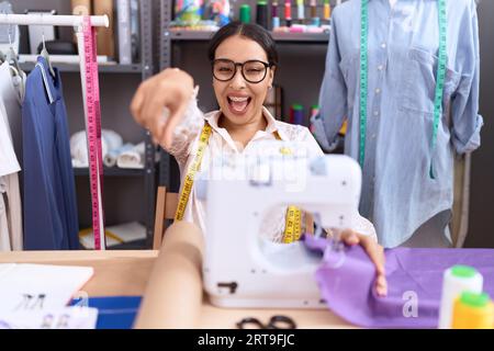 Die junge arabische Schneiderin, die im Atelier arbeitet, zeigt unzufrieden und frustriert auf die Kamera, wütend und wütend auf dich Stockfoto