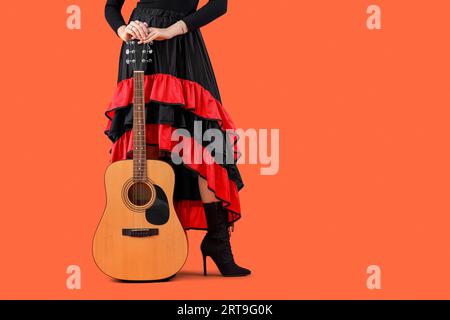 Junge Frau mit Gitarre auf orangem Hintergrund. Feierlichkeiten zum mexikanischen Todestag (El Dia de Muertos) Stockfoto