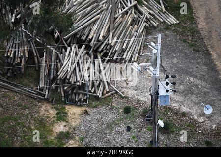 Luftbild der Hardware von Stromversorgungsanlagen über Stapeln aus recycelten Holzmasten. Stockfoto