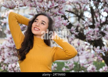 Eine schöne Frau in der Nähe eines blühenden Magnolienbaums am Frühlingstag Stockfoto