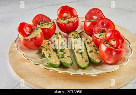 Gefüllte Tomaten und Gurken mit grünen Zwiebeln auf dem Teller Stockfoto