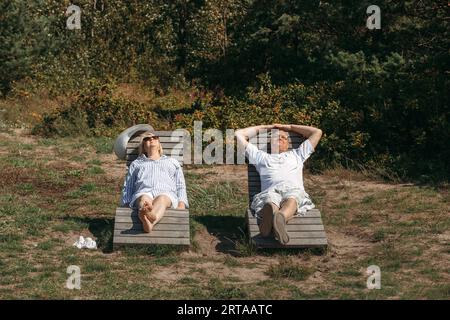 Ein paar süße ältere Leute liegen auf Sonnenliegen und sonnen sich. Stockfoto