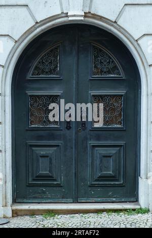 Wunderschönes großes altes altes altes blaues Holzbogentor aus Steinhaus, das mit Schmiedearbeiten, Schnitzereien und Ornamenten verziert ist. Architektur, historisches Gebäude Stockfoto