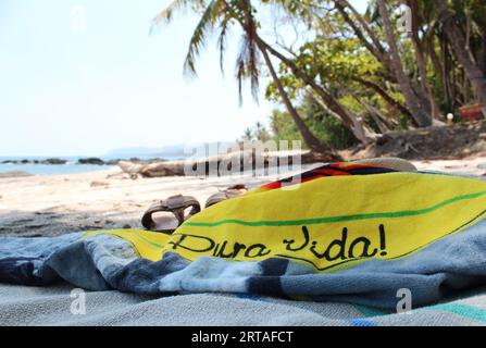 Genießen Sie das Leben an einem paradiesischen Strand in Costa Rica, „pura vida!“ Auf dem Strandtuch bedeutet „einfaches Leben“ oder „reines Leben“, aber in Costa Rica ist es mehr als Stockfoto