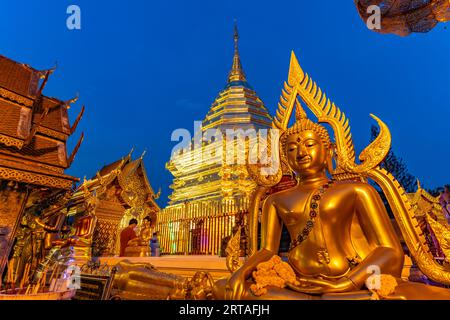 Buddha-Statue und goldene Chedi des buddhistischen Tempelkomplexes Wat Phra That Doi Suthep, Wahrzeichen von Chiang Mai in der Abenddämmerung, Thailand, Asien Stockfoto