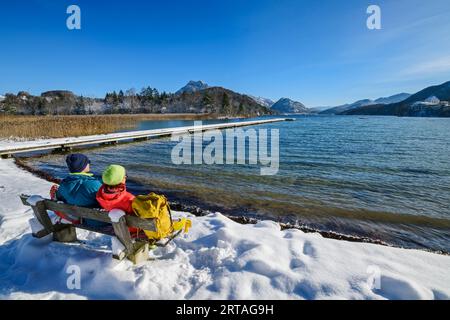 Mann und Frau wandern auf einer Bank sitzend und mit Blick auf Fuschlsee, Fuschlsee, Salzkammergut, Salzkammergut, Salzburg, Österreich Stockfoto