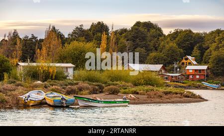 Boote und Häuser am Strand der idyllischen kleinen Stadt Puerto Rio Tranquilo am Lago General Carrera in Chile bei Sonnenuntergang, Patagonien, Südamerika Stockfoto
