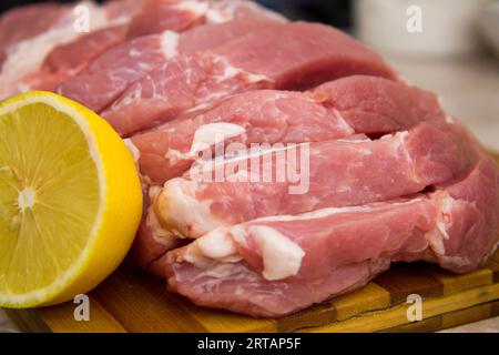 Auf dem Holztisch werden Schweinefleischscheiben zum Kochen von Steak zubereitet Stockfoto