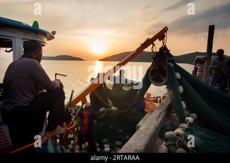 Koh Yao, Thailand; 1. Januar 2023: Fischer entladen den Tagesfang bei Sonnenuntergang von einem Boot im Hafen von Koh Yao. Stockfoto