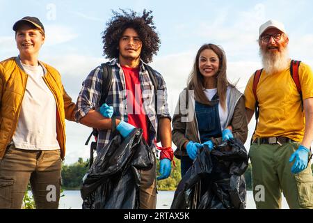 Eine multirassische Gruppe von Freunden aus verschiedenen Altersgruppen trifft sich im Herzen der Natur, bewaffnet mit Gummihandschuhen und Müllsäcken, bereit für eine Mission zur Reinigung der Umwelt. Dieses eindrucksvolle Bild zeigt ihr kollektives Engagement für den Erhalt der Schönheit der natürlichen Welt und verkörpert den Geist der Gemeinschaft und der Verantwortung für die Umwelt. Verschiedene Freunde vereint für die Naturpflege. Hochwertige Fotos Stockfoto