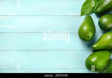 Avocado auf blauem Hintergrund. Avocadofrucht mit Avocadoblättern. Blick von oben auf Avocado. Stockfoto