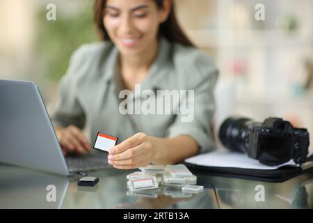 Glücklicher Fotograf, der zu Hause Fotos mit Karte auf den Laptop herunterlädt Stockfoto