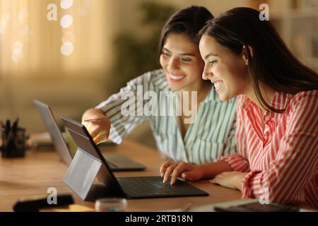 Telearbeiter, die nachts mit mehreren Geräten zu Hause arbeiten Stockfoto