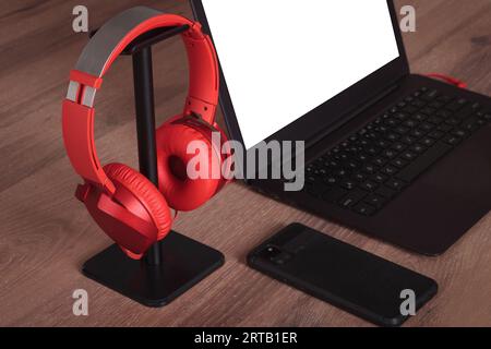 Einrichtung des Arbeitsplatzes: Laptop und rote Kopfhörer auf dem Schreibtisch Stockfoto