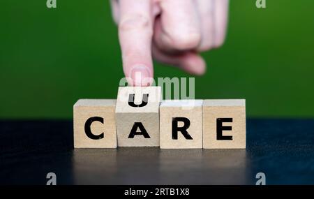Die Hand dreht Holzwürfel und ändert das Wort „PFLEGE“ in „AUSHÄRTEN“. Stockfoto