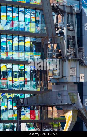 Alter Kran vor der Glasfassade eines Bürogebäudes, das Hochhaus Colorium spiegelt sich darin wider, Fassade mit farbigen Glaspaneelen, Architekt W Stockfoto