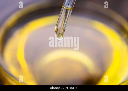 Gelbe Textur eines Tropfens Molke oder Olivenöl auf gelbem Hintergrund. Transparente Probe des kosmetischen Gels mit Blasen. Goldene Säure-Creme. Vitamin c. a Stockfoto
