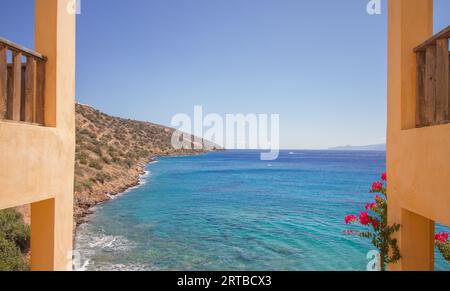 Blick auf das türkisfarbene mittelmeer auf der Insel Kreta, Griechenland, mit traditionellen Gebäuden und Blumen, in der Nähe von Agios Nikolaos Stockfoto