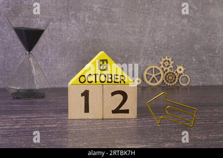 Oktober. Hallo Oktober, Cube Holzkalender mit Datum am 12. Oktober, Holzkalender mit Unschärfe-Objekten auf dem Hintergrund. Stockfoto