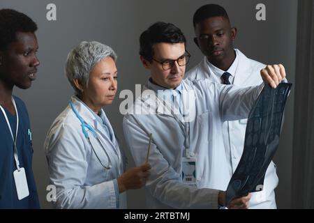 Gruppe von vier erfahrenen Radiologen, die sich das Röntgenbild des Patienten anschauen und seine Eigenschaften auf der Arbeitssitzung im Krankenhaus diskutieren Stockfoto