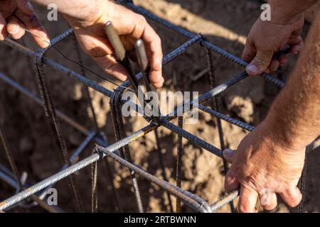 Zwei Arbeiter, die eine Schalungsstange für Fundamente eines Gebäudes verstärken Stockfoto