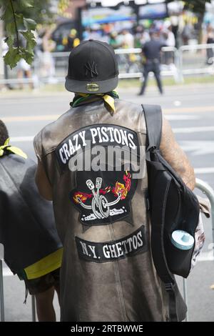 Mitglied des „Crazy Pistons Motorcycle Club“, der mit „Bikern für Babys“ arbeitet und Windeln und andere Gegenstände verteilt. Zuschauer am Eastern Parkway bei der jährlichen West Indian Caribbean Parade am Labor Day in Brooklyn, New York. Stockfoto