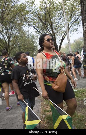 Mutter und Sohn mit jamaikanischen Flaggen beobachten die Parade. Zuschauer am Eastern Parkway bei der jährlichen West Indian Caribbean Parade am Labor Day in Brooklyn, New York. Stockfoto