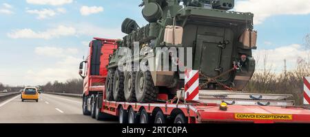 Rückansicht gepanzerter Personentransporter stryker mit Luftverteidigungssystem Anhänger Spediteur LKW-Antrieb Militärkonvoi Autobahn Straße. US-Truppen bewegen sich Stockfoto