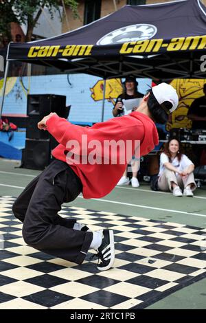 Break Dancer in Red Hoodie Back Hose und schwarzen adidas Sneakers – kniebend Breakdance Performance, Wettkampf und Schlachten Woolloomooloo, Sydney Stockfoto