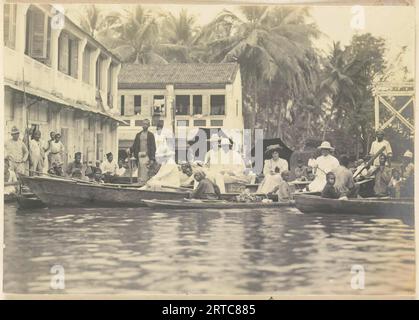 West Sumatra, Indonesien, 1900, Vintage-Archivfoto, Offizielle der Gesellschaft der Europäer, segelt mit Booten durch die überfluteten Straßen von Tandjong Poera, Langkat Sumatra Stockfoto