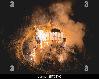 Braten von Würstchen über einem Lagerfeuer. Zeit mit Freunden verbringen. Stockfoto