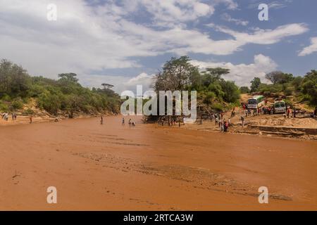 OMO VALLEY, ÄTHIOPIEN - 4. FEBRUAR 2020: Menschen überqueren den Kizo-Fluss in Äthiopien Stockfoto