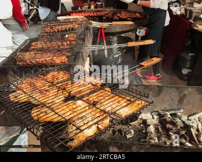 Barbecue Fleisch Hähnchen Schweinefleisch gegrilltes Rindfleisch auf offenem Feuer rauchige Kohlen, Koch bereitet eine Menge Essen für Gäste Festival Essen Stockfoto