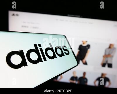 Mobiltelefon mit Logo des deutschen Bekleidungs- und Schuhherstellers Adidas AG auf dem Bildschirm vor der Website. Konzentrieren Sie sich auf die Mitte-links-Anzeige des Telefons. Stockfoto