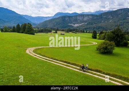 Mountainbiker auf der lokalen Schotterstraße radeln durch die wunderschöne Landschaft in der Nähe des Bohinj-Sees und des Triglav-Nationalparks in Slowenien Stockfoto