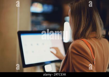 Frau zahlt an Selbstcheckouts im Supermarkt. Stockfoto
