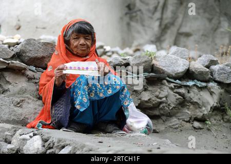 Frau mit ihrer Näharbeit im alten Dorf Ganish im Hunza-Tal Stockfoto