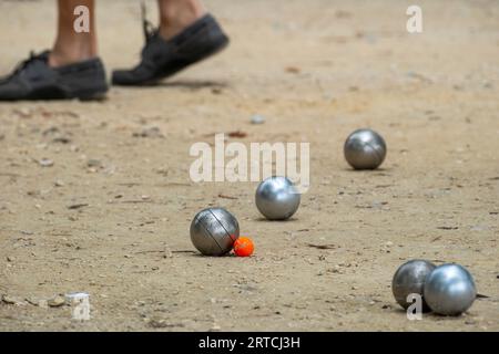 Petanque Ball Boules Schüsseln auf einem Staubboden, Foto beim Aufprall. Petanque-Spiel auf dem Boden. Kugeln und einen kleinen Holzheber. Stockfoto