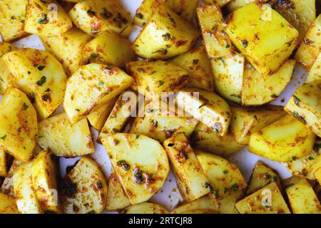 Rohe Kartoffelscheiben in der Draufsicht der Gewürze. Frische Kartoffelspalten, die auf rustikale Weise mit Kräutern und Gewürzen gemischt werden und zum Backen oder Braten bereit sind. Rohe Kartoffeln mit Stockfoto