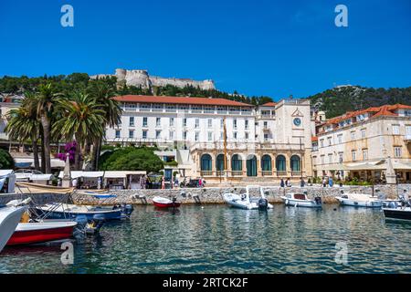 Palace Hotel, Loggia und Uhrenturm, mit spanischer Festung auf einem Hügel über Hvar Stadt (Grad Hvar) auf der Insel Hvar an der dalmatinischen Küste von Kroatien Stockfoto