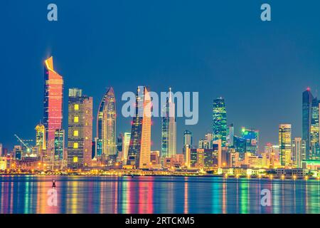 Blick auf die Skyline von Kuwait vom Strand aus während der Nationalfeiertage. Kuwait National Tageslichter auf dem Gebäude und Kuwait Flagge Lichter während der Nacht Stockfoto