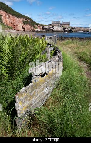 Blick auf einen verlassenen Hafen mit einem alten Holzboot im Vordergrund, East Lothian, Schottland, Vereinigtes Königreich Stockfoto