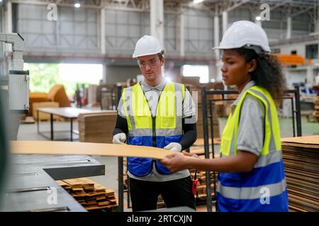 Industriearbeiter in der Fabrik. Junger Techniker mit orangem Schutzhelm. Kluger kaukasischer Fabrikarbeiter, der einen Hut trägt und im Kraftwerk arbeitet Stockfoto