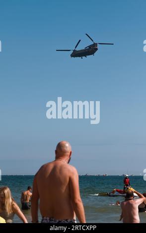 Mann, der am Strand steht und Einen Chinook Hubschrauber beobachtet, der während der Bournemouth Air Show, England, Großbritannien, auftritt Stockfoto