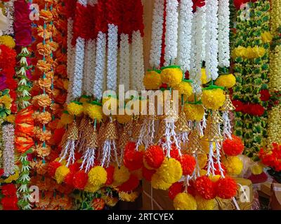 Mehrfarbige künstliche Blumen, die für die Dekoration des Diwali-Festivals verwendet werden und in einem Geschäft am Tag vor dem Diwali- und Ganesh-Festival hängen Stockfoto