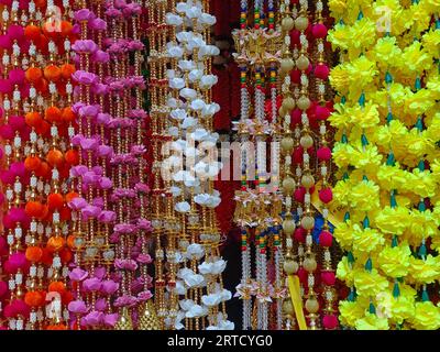 Mehrfarbige künstliche Blumen, die für die Dekoration des Diwali-Festivals verwendet werden und in einem Geschäft am Tag vor dem Diwali- und Ganesh-Festival hängen Stockfoto